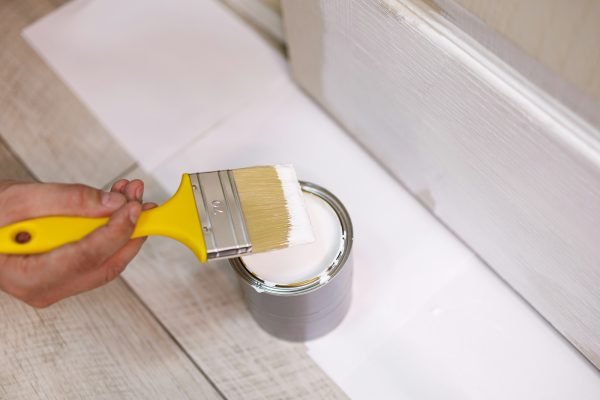 Close-up of a can of paint in which the brush is dipped. Repair staining the doors with paint.